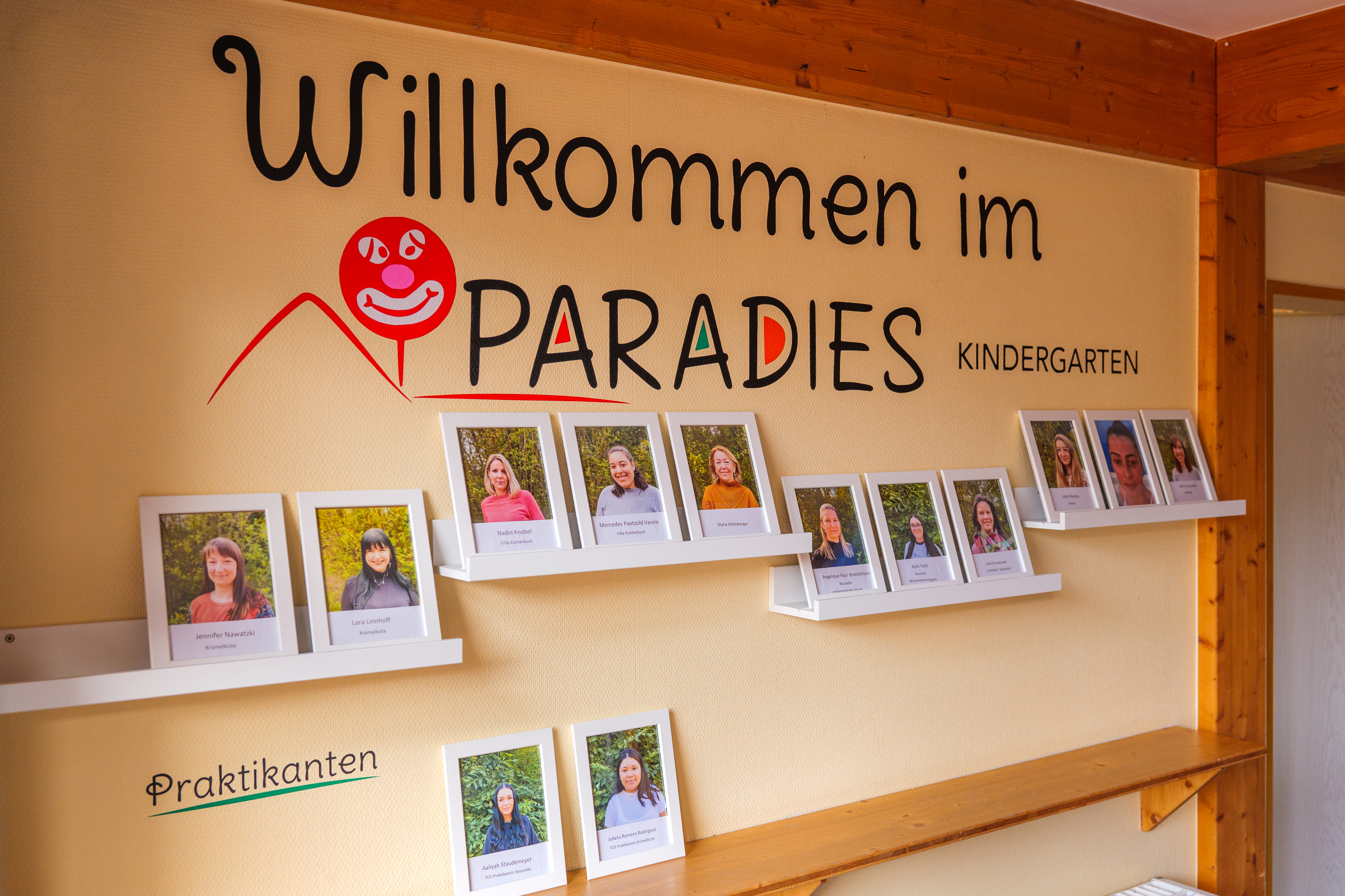 Mitarbeitende stehen jeweils mit Bild an der Wand