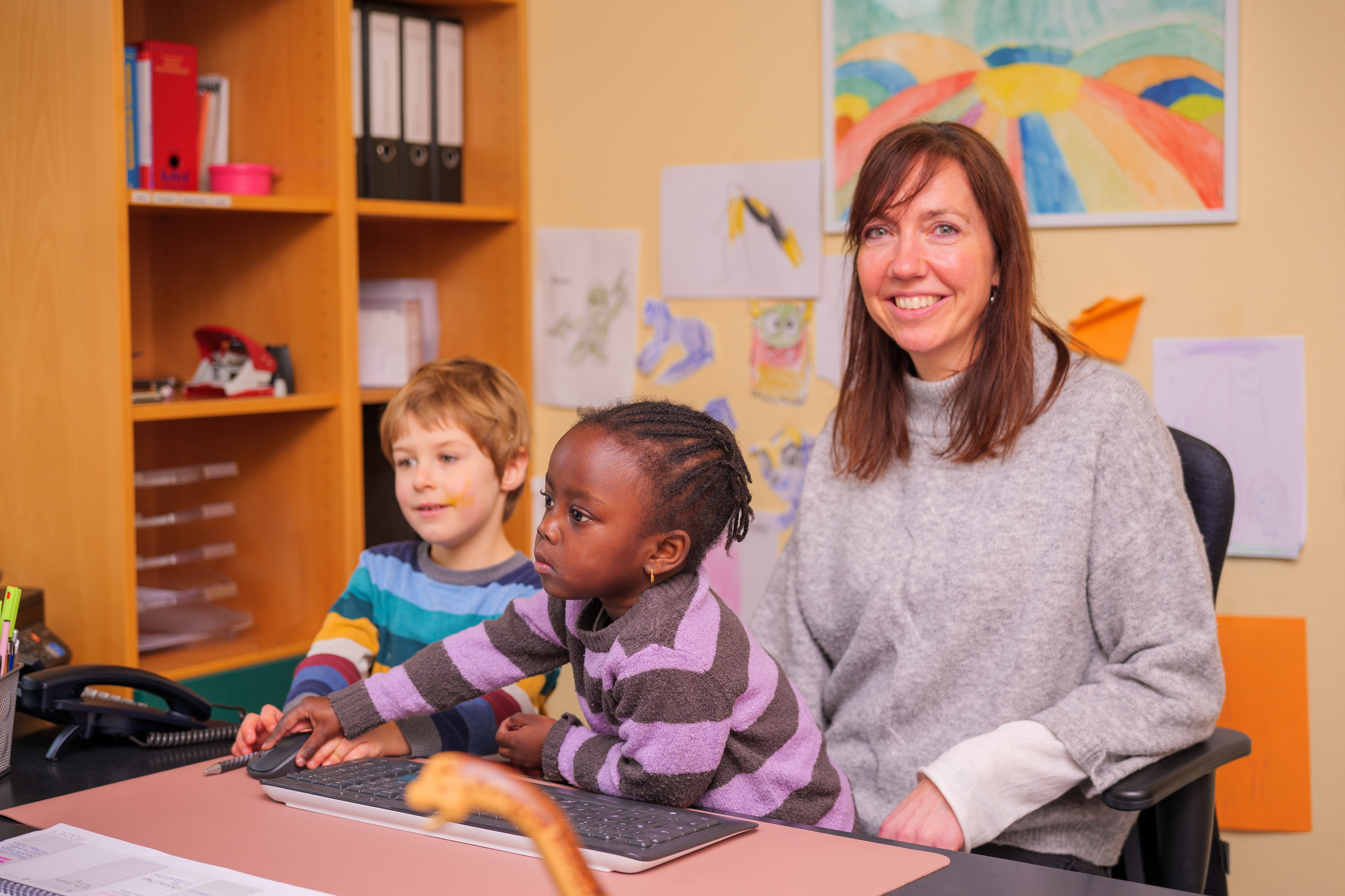 Frau sitzt mit Kindern am PC