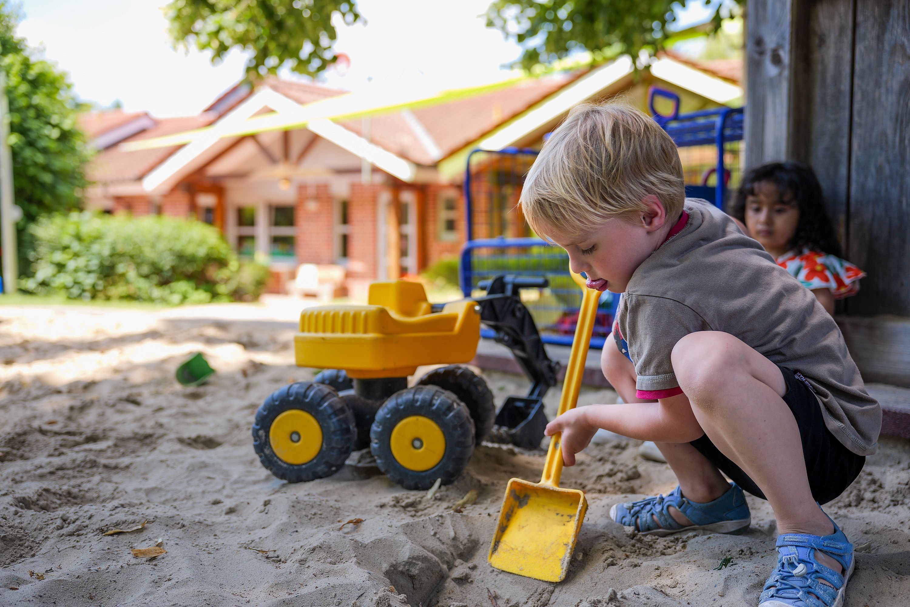 Junge spielt mit einer Schaufel im Sand