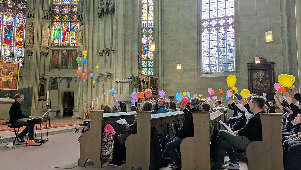 Menschen freuen sich und halten bunte Luftballons in die Luft