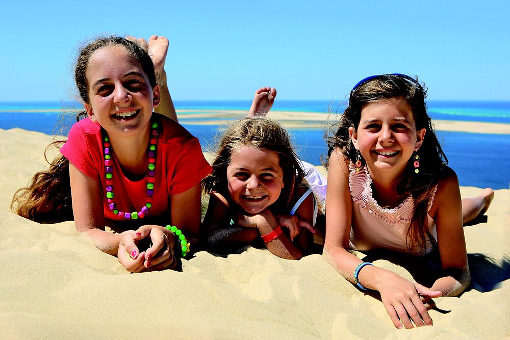Kinder liegen am Strand und freuen sich