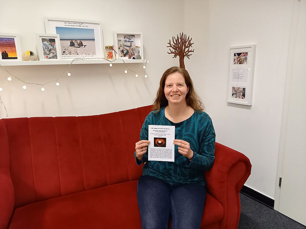 Frau sitzt mit Flyer auf einem Sofa
