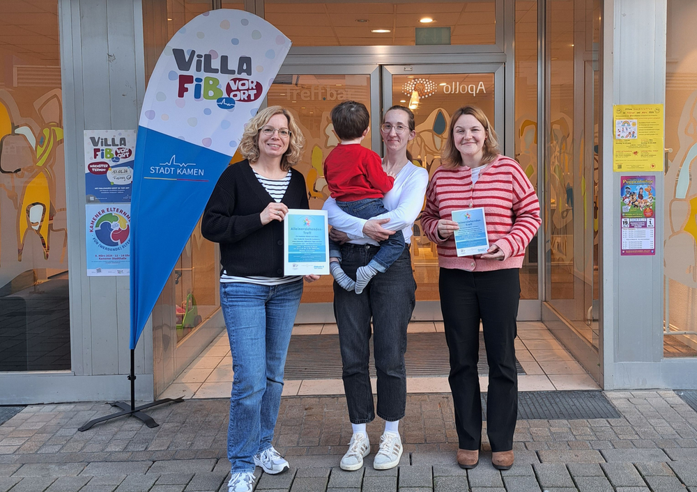 Foto zeigt zwei Mitarbeiterinnen und Mutter mit Kind auf dem Arm vor Treff