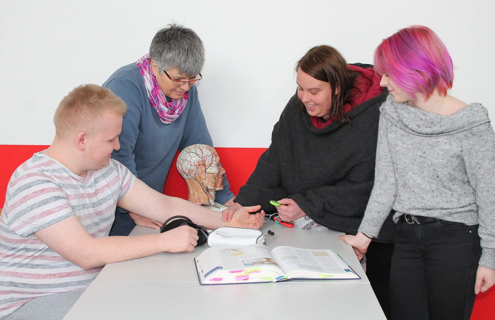 Lehrerin zeigt, wie man richtig Blutdruck misst.